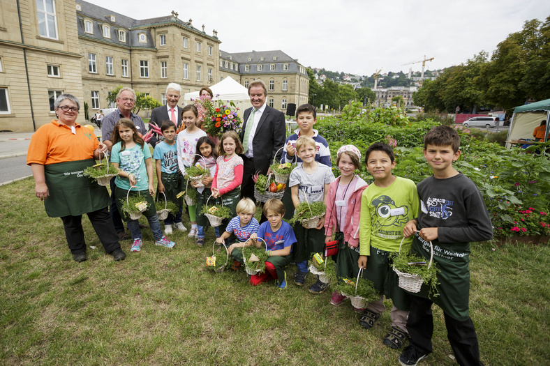 Eine Gruppe von Kindern und Erwachsenen mit Minister Untersteller vor dem Neuen Schloss auf der Wiese.