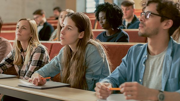 Dargestellt sind Studentinnen und Studenten während einer Vorlesung im Hörsaal.