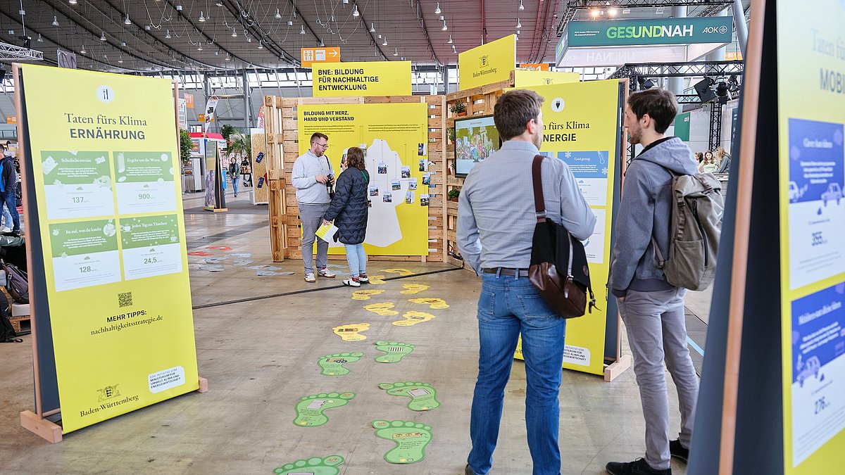 Besucherinnen und Besucher betrachten die Informationstafeln des Messestandes.