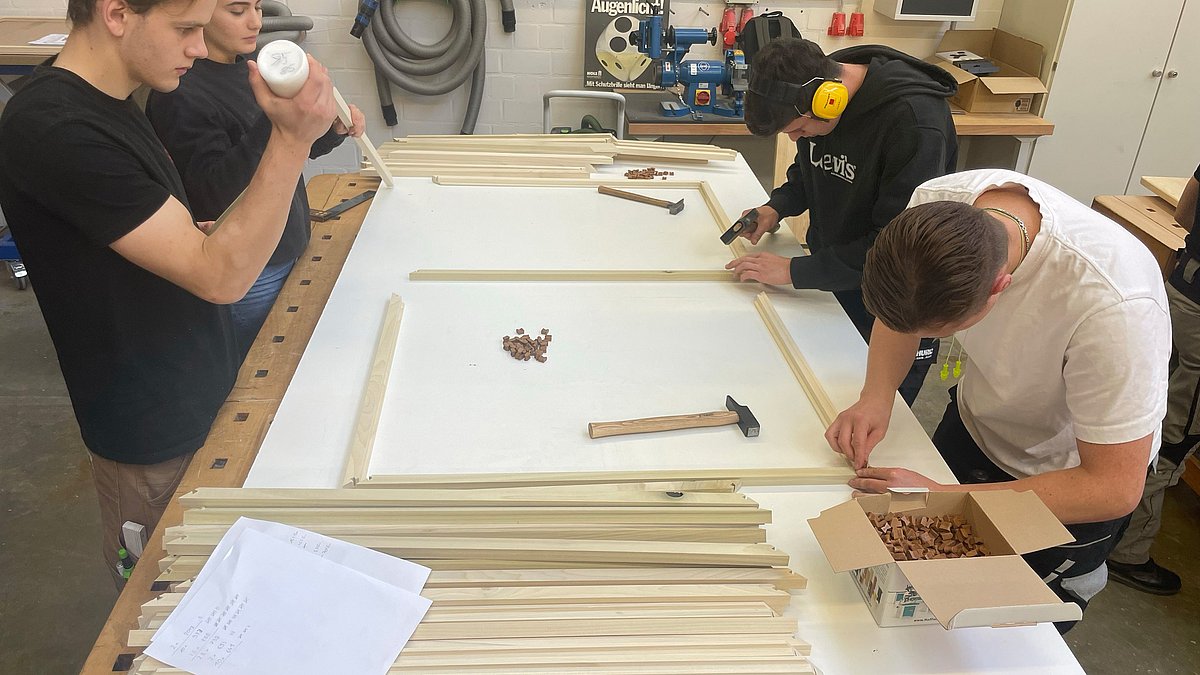 Jugendliche stellen Holzrahmen her.