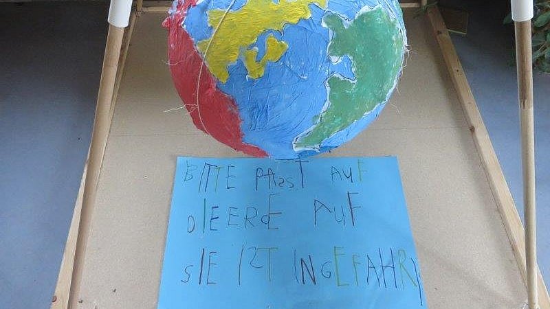Die fertige Weltkugel ausgestellt im Eingang unserer Kita mit einer Aufforderung an alle die uns besuchen.
