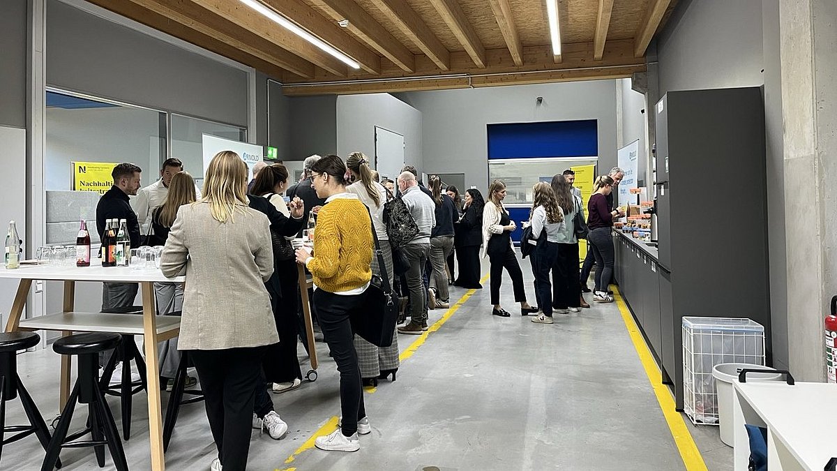 Besuchende des Transformationsworkshops stehen im Gang an verschiedenen Stehtischen.