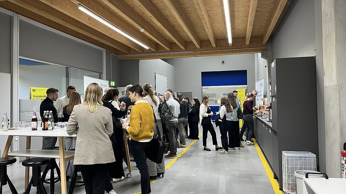 Besuchende des Transformationsworkshops stehen im Gang an verschiedenen Stehtischen.