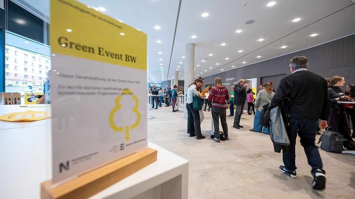 Schild für die Auszeichnung als Green Event im Design des Landes, gelb-schwarz in einem Foyer bei einer nachhaltigen Veranstaltung.