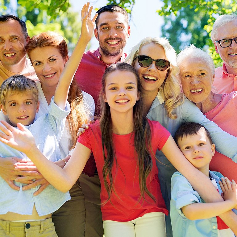 Eine Gruppe Menschen aus allen Altersstufe blickt fröhlich auf den Betrachter.