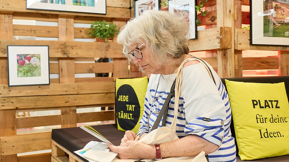 Eine Frau sitzt lesend am Stand der Nachhaltigkeitsstrategie.