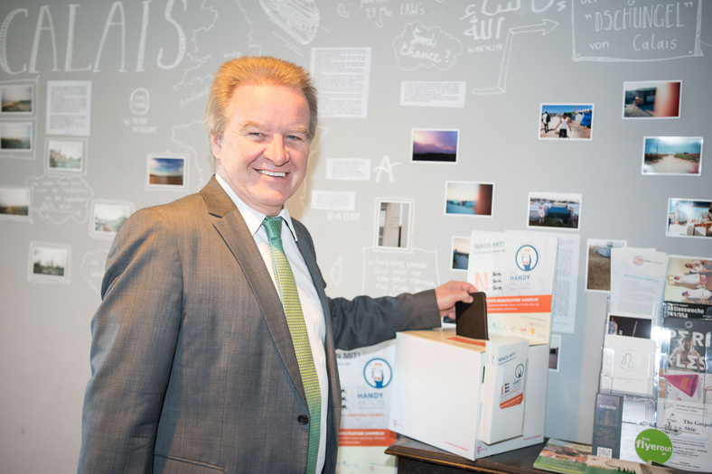 Herr Minister Franz Untersteller posiert vor Recycling-Aktion von alten Handys in baden-württembergischen Gymnasien