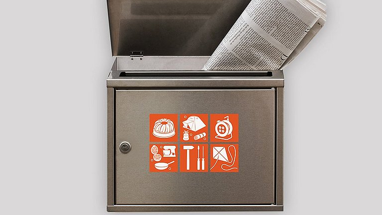 Auf einem Briefkasten kleben verschiedene Aufkleber, mit denen bekanntgegeben wird, was mach sich in diesem Haushalt ausleihen kann.
