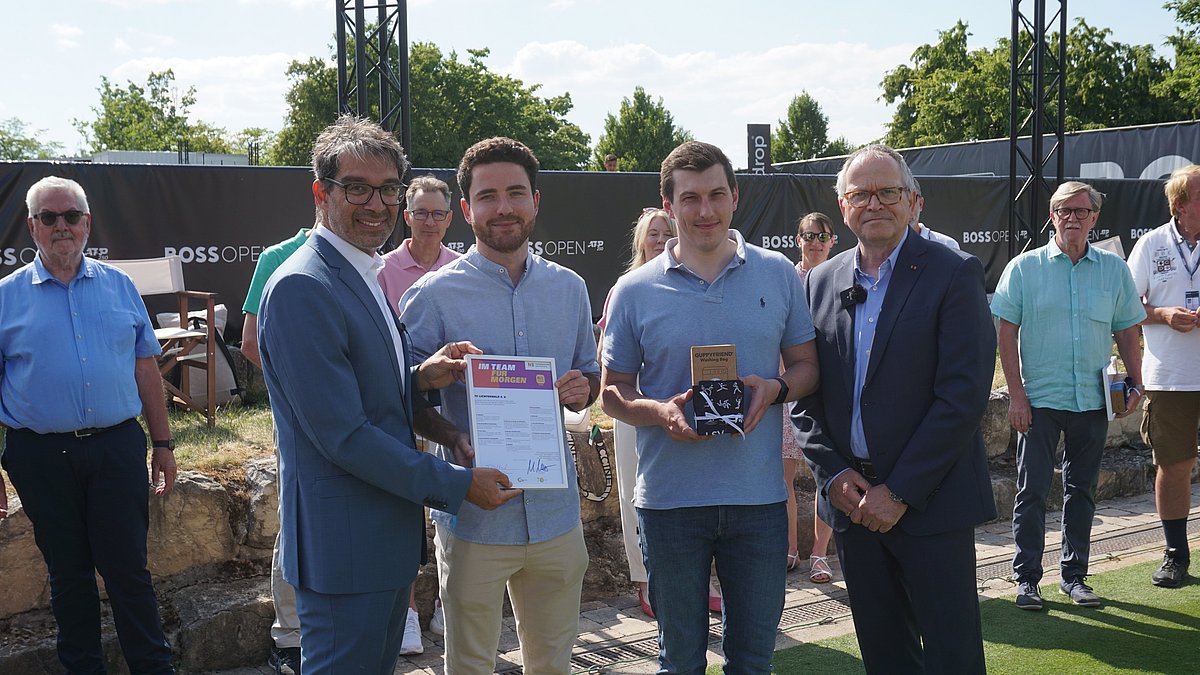 Staatssekretär Andre Baumann steht neben Mitgliedern des TC Lichtenwald und überreicht die N!-Charta Sport Urkunde.