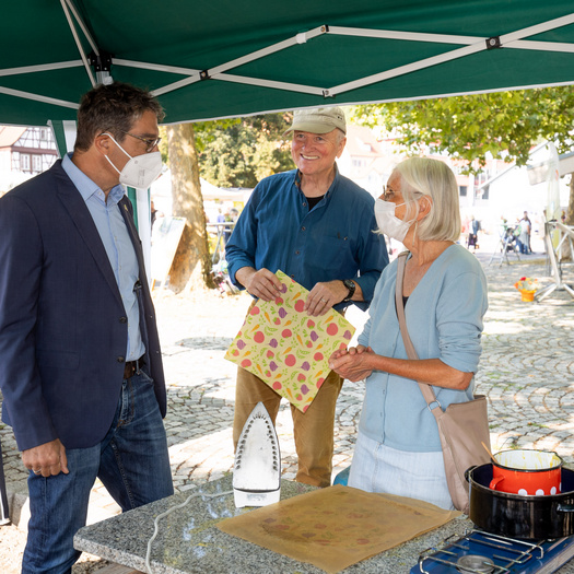 Drei Personen, die sich an einem Stand unterhalten. Links ist Dr. Andre Baumann zu sehen.