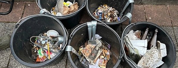 Mehrere schwarze Eimer mit Müll.