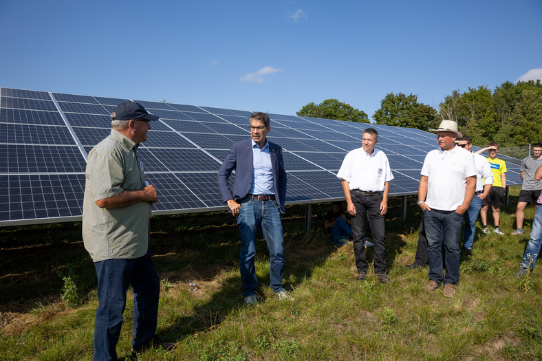 Mehrere Personen, darunter Dr. Andre Baumann, die vor einer Photovoltaik-Anlage stehen.
