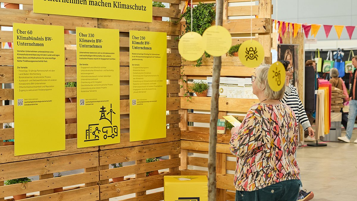 Eine Frau steht vor gelben Tafeln mit "Unternehmen machen Klimaschutz".