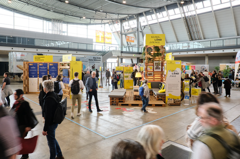 Der Messestand aus der Ferne fotografiert mit vielen Besucherinnen und Besuchern. 