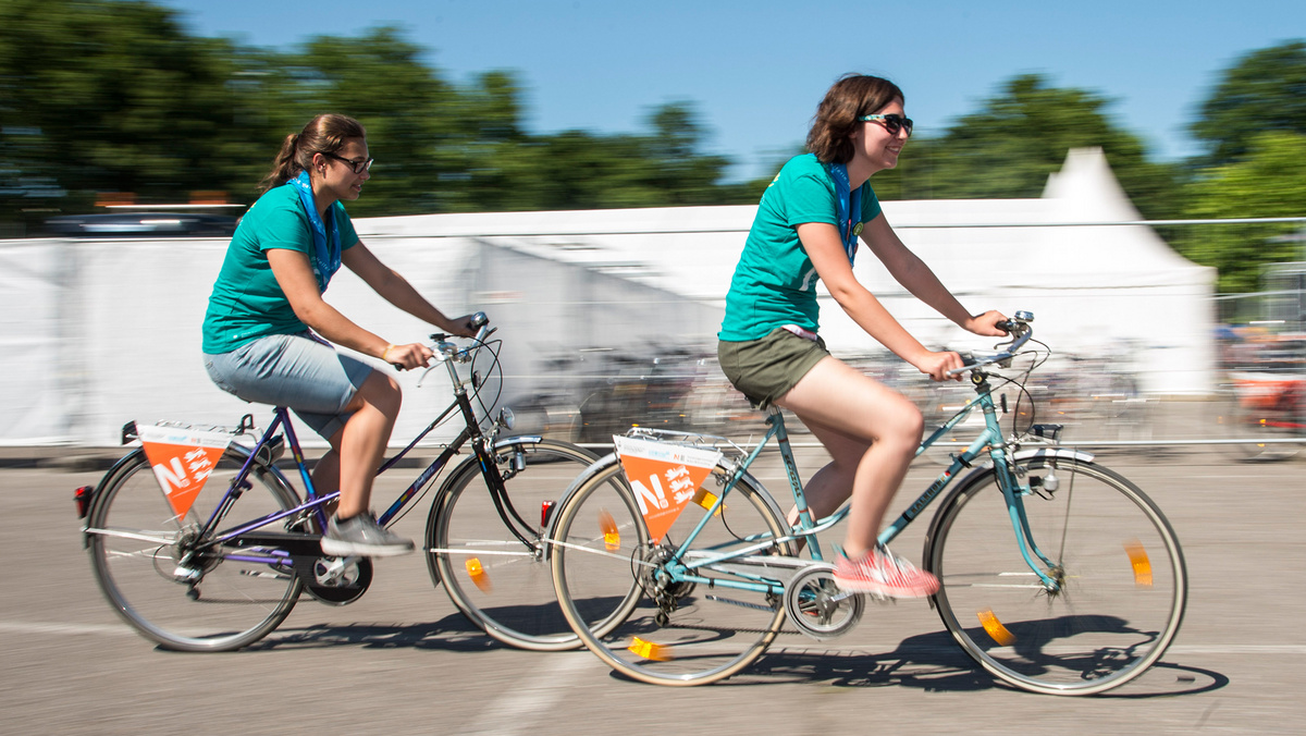 Zwei Frauen sind auf Fahrrädern unterwegs. An den Gepäckträgern hängen Wimpel der Nachhaltigkeitsstrategie Baden-Württemberg.