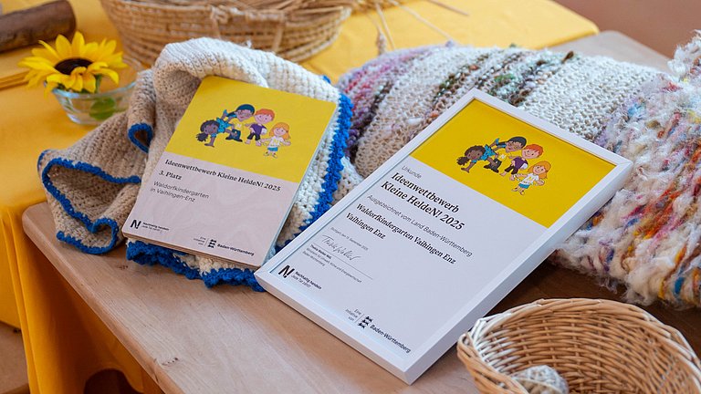 Kleine HeldeN!-Urkunde 2025 liegt auf dem Tisch neben den Wolle-Produkten des nachhaltigen Projekts des Kindergartens.