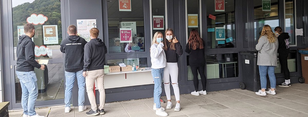 Schülerinnen und Schüler bei der Ausstellung vor der Fensterfront der kaufmännischen Schule.