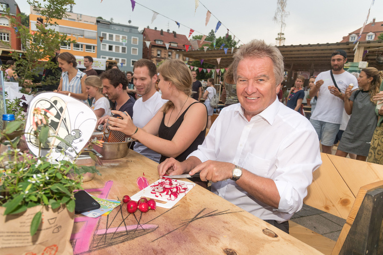 Umweltminister Franz Untersteller schneidet Radieschen beim Foodsharing Dinner auf dem Übermorgen Markt