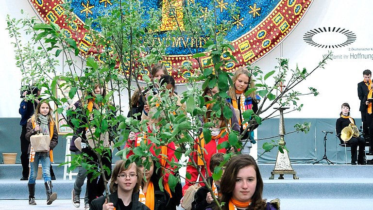In der Kirche der Griechisch-orthodoxe Kirchengemeinde Reutlingen wird der Tag der Schöpfung gefeiert. Kinder tragen Baumsetzlinge.