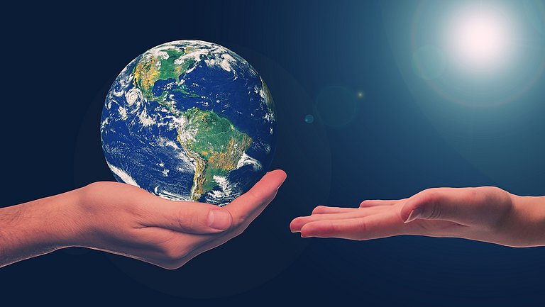 Eine Hand hält schützend die Erdkugel, ihr gegenüber ist eine weiter Hand bereit die Erde in Empfang zu nehmen.