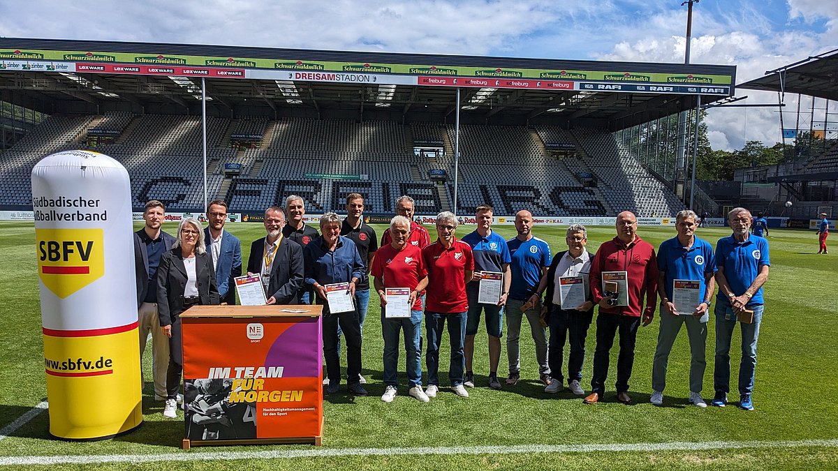 Ein Gruppenbild der gewürdigten Vertreterinnen und Vertreter der Fußballvereine auf dem Fußballfeld.