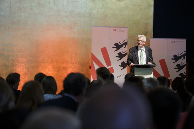 Nachhaltigkeitstage 2014 Ministerpräsident Kretschmann steht auf der Bühne hinter dem Rednerpult und spricht zum Publikum.