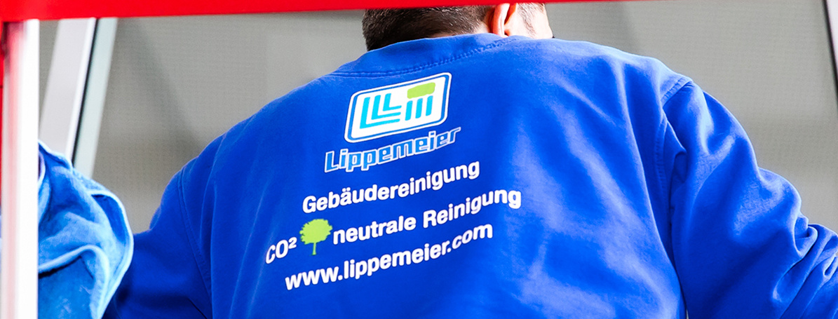 Der Rücken eines Mannes von hinten, der einen dunkelblauen Pulli trägt, auf dem das Logo der Lippemeier GmbH abgebildet ist.
