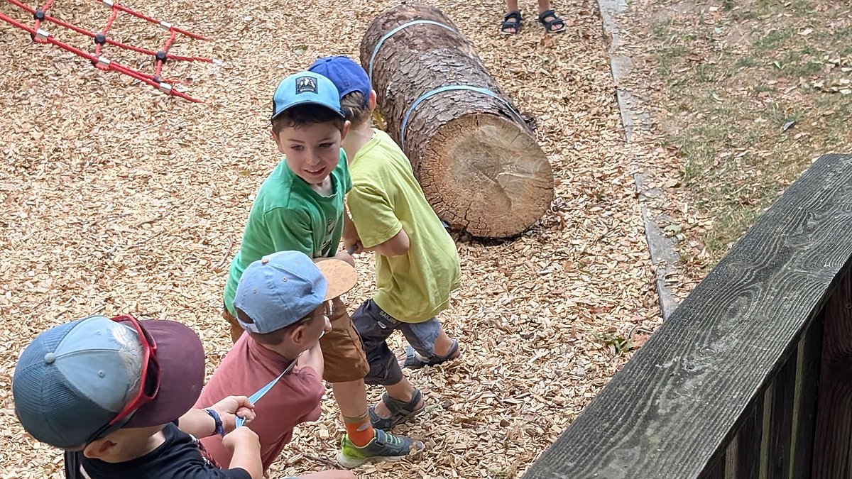 Kinder ziehen einen Baumstumpf