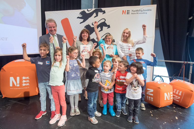 Herr Minister Franz Untersteller posiert mit jubelnden Kindern und drei Erzieherinnen für ein Foto