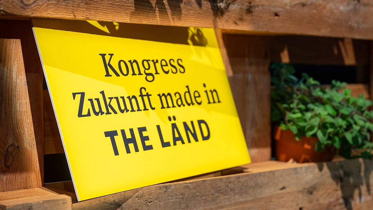 Schild mit schwarzer Schrift auf gelbem Hintergrund „Kongress Zukunft made in the LÄND"