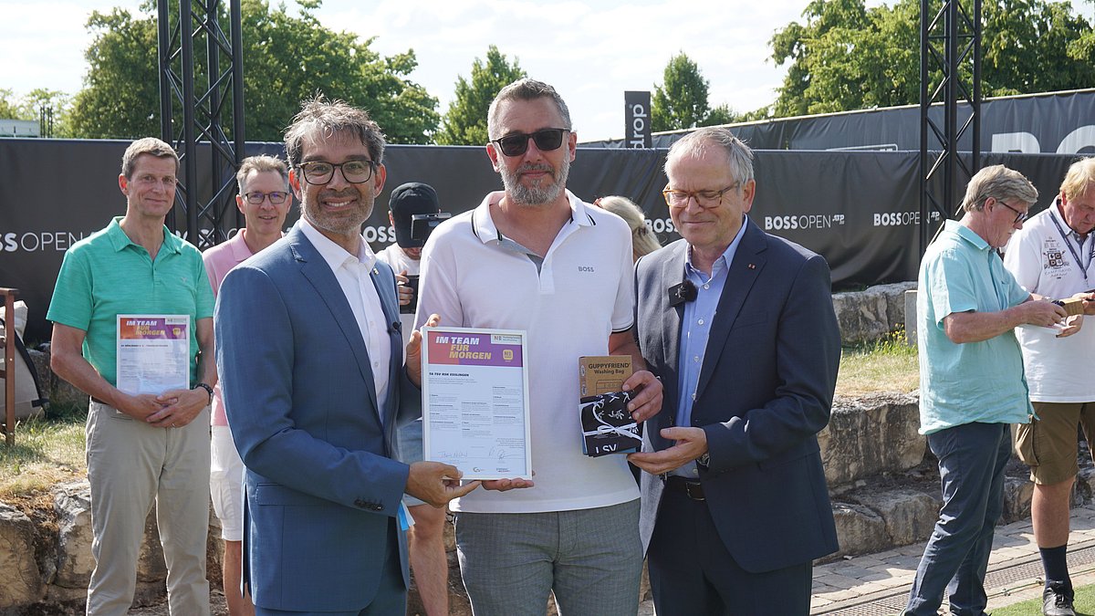Staatssekretär Andre Baumann steht neben Mitgliedern des TA TSV RSK Esslingen und überreicht die N!-Charta Sport Urkunde.