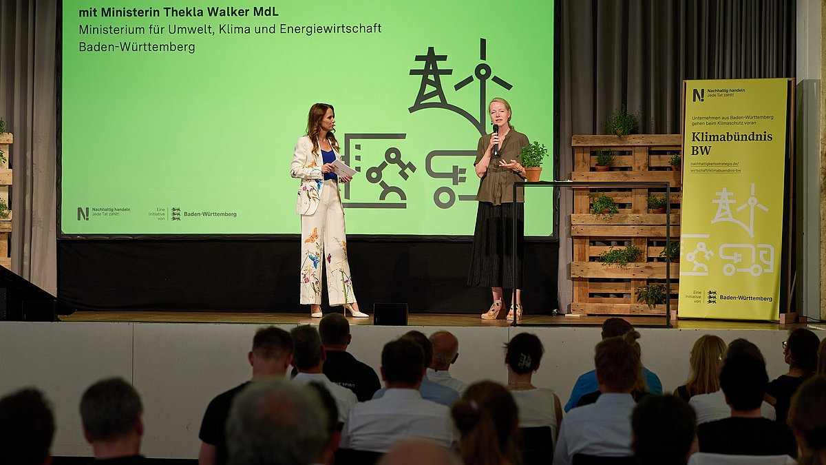 Moderatorin Frau Schöne und Umweltministerin Thekla Walker MdL auf der Bühne zur Begrüßung der Unternehmensvertreterinnen und -vertreter.