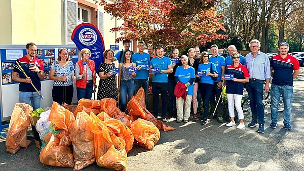Mitglieder des tsg Seckenheim bei der ersten kipp it clean Aktion mit orangenen Müllsäcken vor sich.