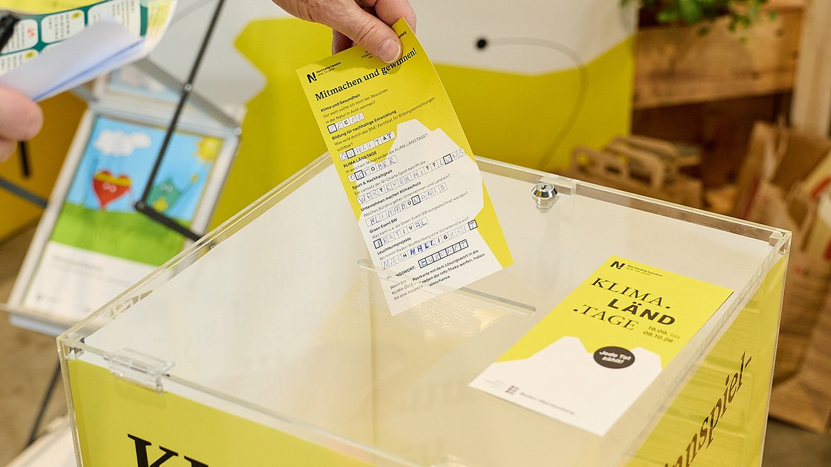 Ein Laufzettel wird in eine Gewinnspiel-Box geworfen.