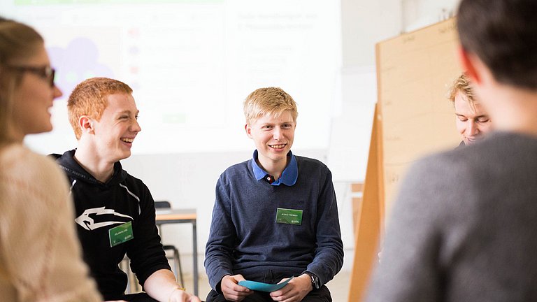 Nahaufnahme von Schülern im Sitzkreis.