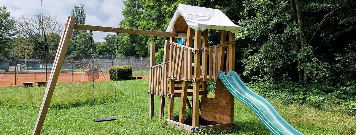 Spielturm mit Rutsche auf dem Rasen des Vereinsgeländes des TC Besigheim.
