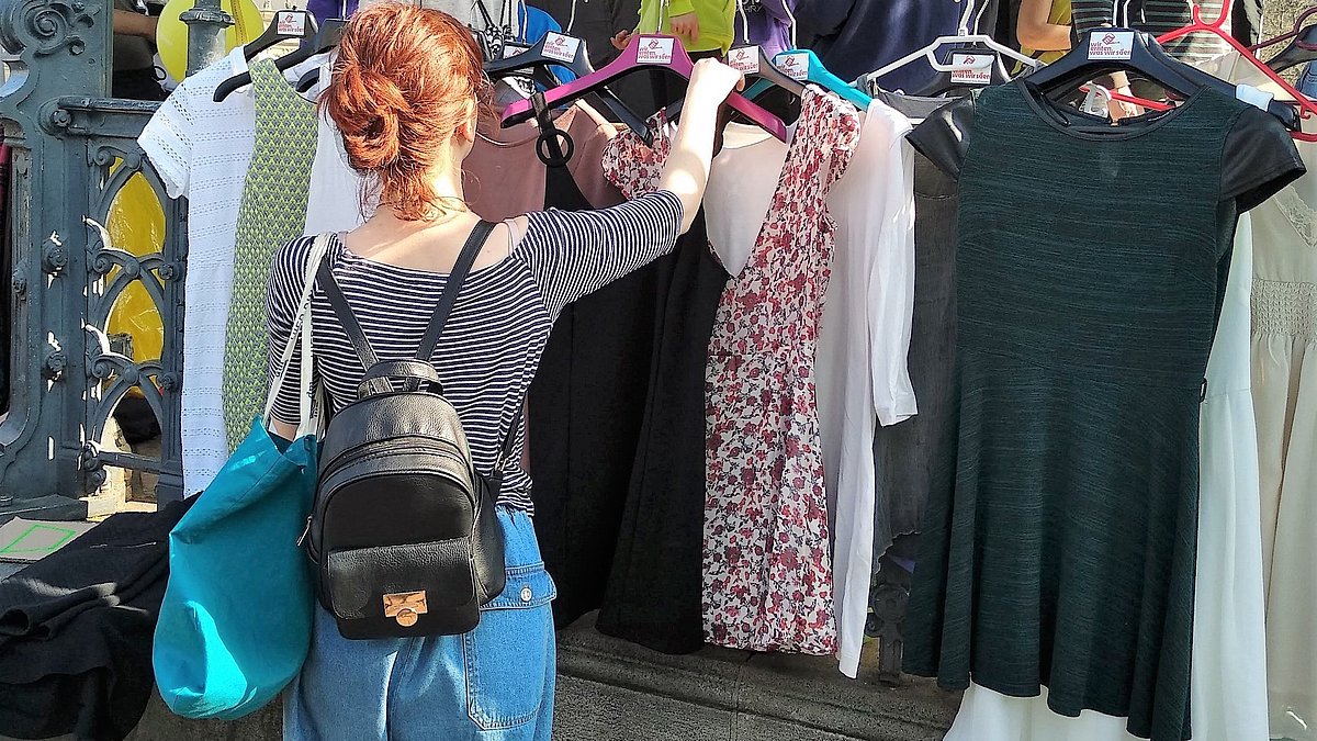 Frau betrachtet Second Hand Klamotten.