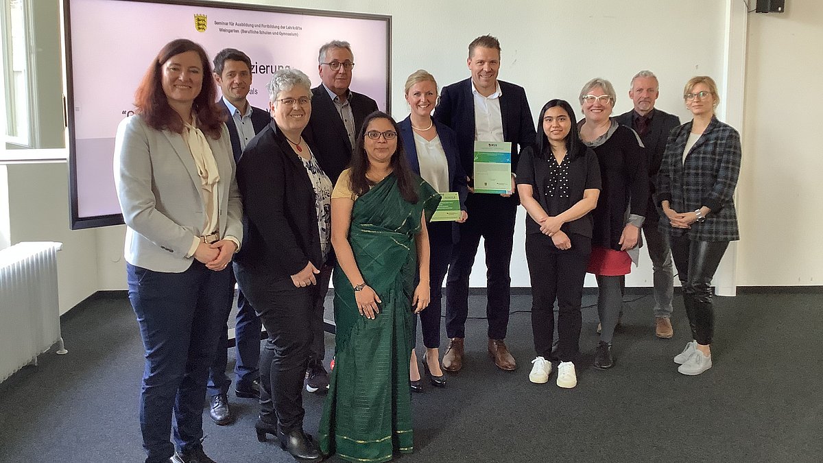 Mehrere Personen stehen in einem Raum vor einer Präsentationswand