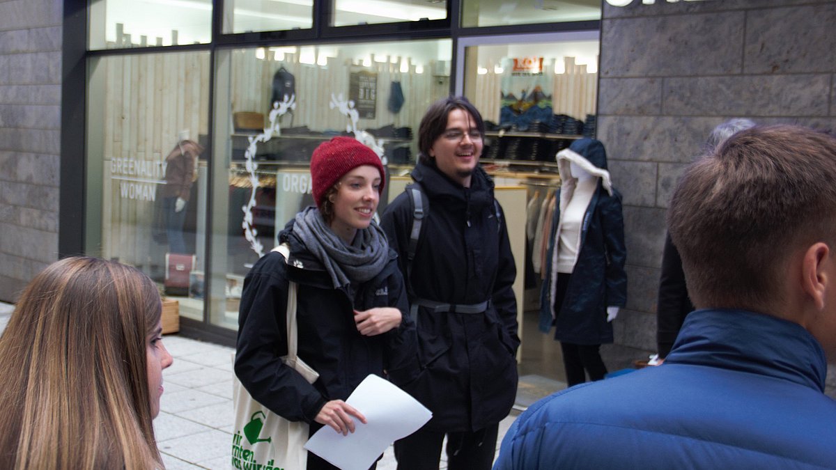 Aufnahme von zwei Teilnehmenden der Tour vor einem Klamottenladen.
