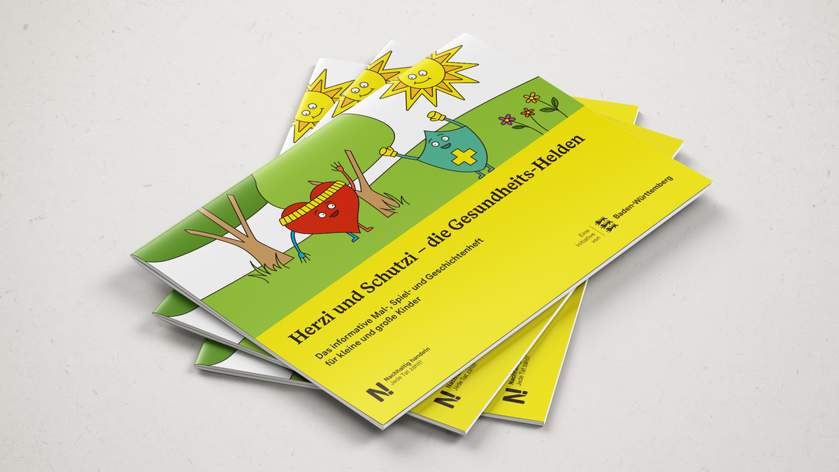 Drei Malbücher, Herzi und Schutzi, die Gesundheitshelden, liegen übereinander auf einer grauen Fläche.