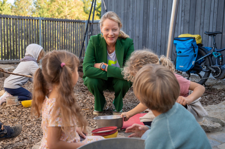 Umweltministerin Thekla Walker spricht mit Kindern im Garten.