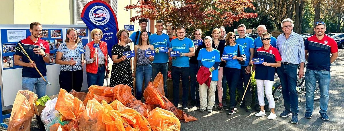 Mitglieder des tsg Seckenheim bei der ersten kipp it clean Aktion mit orangenen Müllsäcken vor sich.