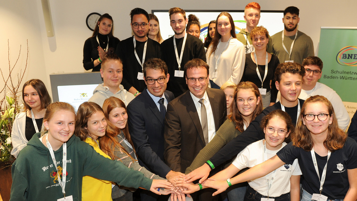 Staatssekretär Andre Baumann und Staatssekretär Volker Schebesta drücken mit Schülerinnen und Schülern in der Klima Arena in Sinsheim den Startknopf für das neue BNE-Schulnetzwerk.