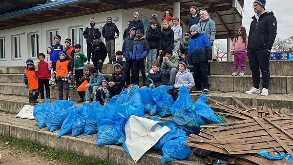 Mehrere Vereinsmitglieder von SV Blau-Weiß Wiehre stehen vor blauen Müllsäcken.