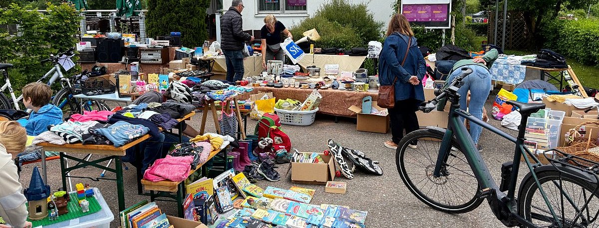 Flohmarktstände vor einem Restaurant, es sind beispielsweise Bücher und Schuhe zu sehen.