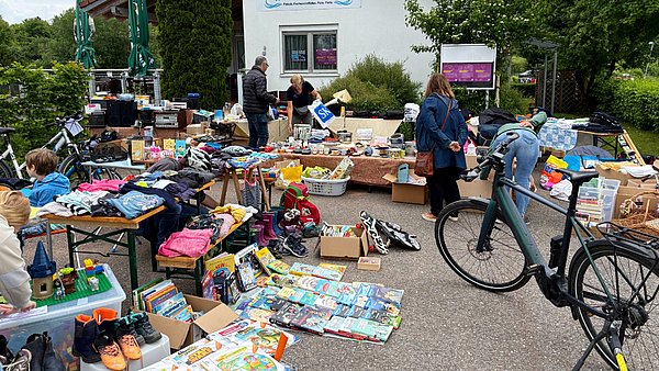 Flohmarktstände vor einem Restaurant, es sind beispielsweise Bücher und Schuhe zu sehen.