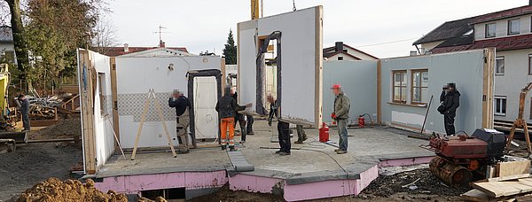 Aufbau eines Fertighauses durch einzelne Wände die von einem Kran zusammengesetzt werden.