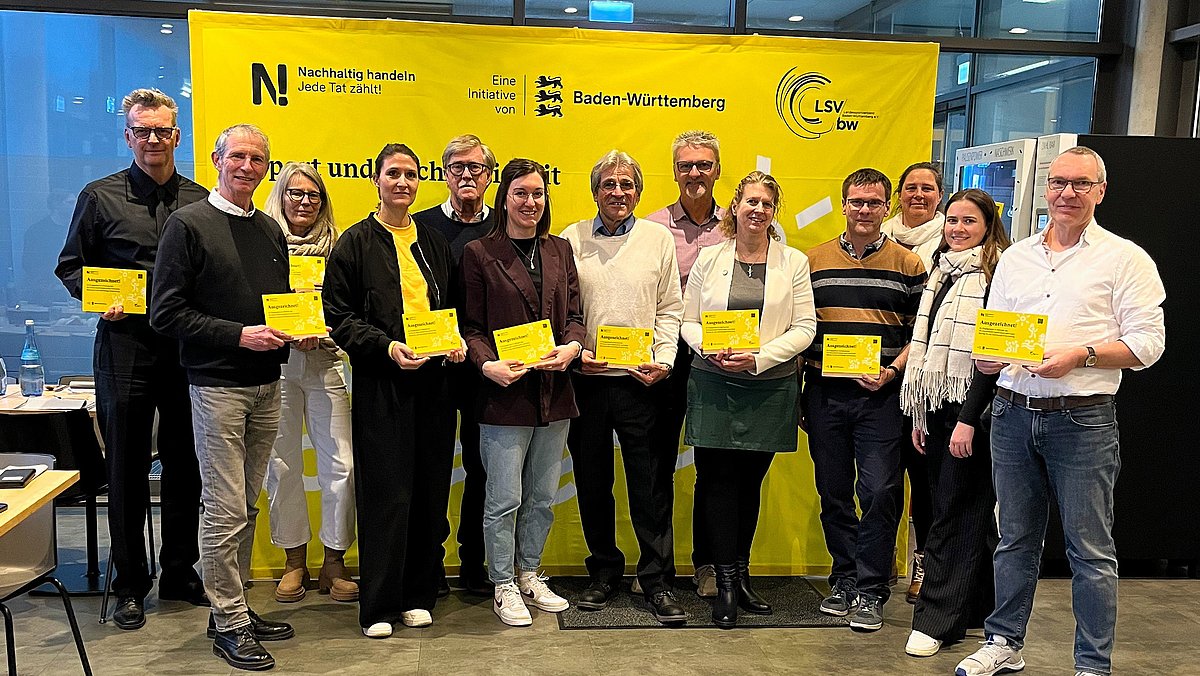 Alle geehrten Vertreterinnen und Vertreter der Vereine und Verbände stehen mit ihrer Auszeichnungs-Plakette zusammen für das Gruppenfoto 