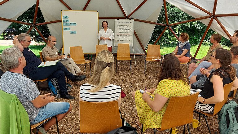 Workshoprunde unter einem Zeltdach.