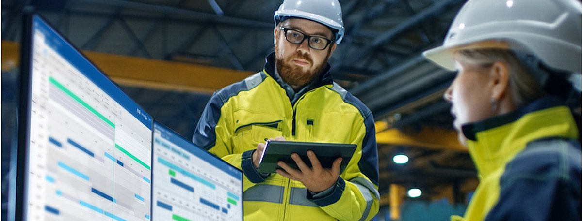 Arbeiterin und Arbeiter arbeiten an einem Terminal